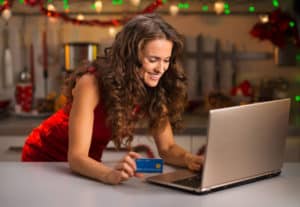 Woman With Credit Card Typing On Laptop In Christmas Kitchen